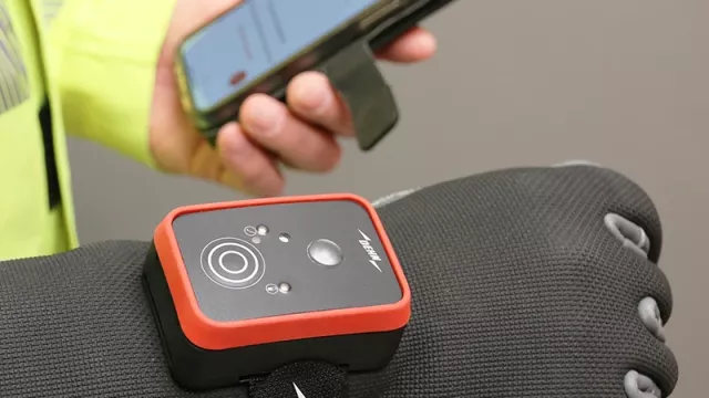 A electrical field detector showcases a sleek red and black design with a prominent white circle. The detector, held by a black-gloved hand with a white logo, presents a modern safety tool. Its compact positioning ensures field professionals can detect electrical fields with style and precision.